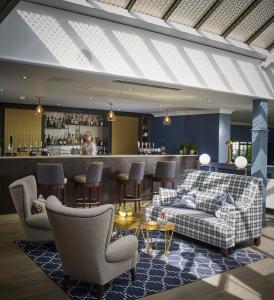 a lobby with couches and a bar in the background at Tewkesbury Park in Tewkesbury