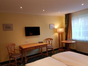 a hotel room with a desk and chairs and a television at Hotel Fliegerheim in Borkheide