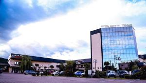 a large glass building with cars parked in a parking lot at Hotel Crystal Palace in Râmnicu Vâlcea