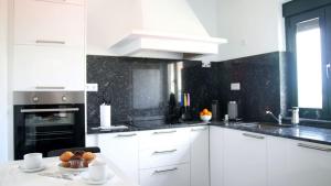 a kitchen with white cabinets and a sink and an oven at Apartamentos AUGA in Fene