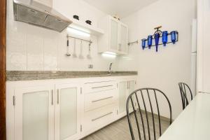 eine Küche mit weißen Schränken und einem Tisch und Stühlen in der Unterkunft Los Topes in Puerto del Carmen + 36 Fotos