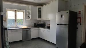 eine Küche mit weißen Schränken und einem Kühlschrank in der Unterkunft Villa spacieuse proche de L'océan in Vila Praia de Âncora
