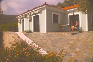 a woman sitting on the porch of a house at Villa Platanaki in Kerveli