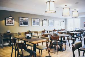 een eetkamer met tafels en stoelen en foto's aan de muur bij Cyan Soho Neuquén Hotel in Neuquén