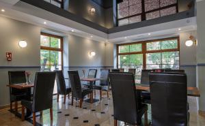 uma sala de jantar com mesas, cadeiras e janelas em Akacja Medical Resort em Ciechocinek