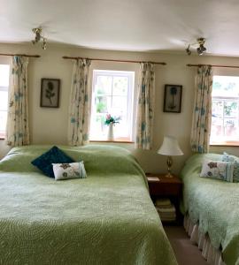 two beds in a bedroom with two windows at High Mead in Woodsford