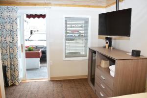 a living room with a tv and a dresser with a television at Alouette Beach Resort Economy Rooms in Old Orchard Beach