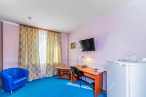 a room with a desk and a tv and a blue chair at Hotel Filton in Tyumen