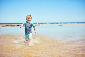 Un ragazzo che correva attraverso l'acqua sulla spiaggia di Anglesea Family Caravan Park a Anglesea