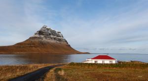 una casa con techo rojo frente a una montaña en Hellnafell, en Grundarfjordur