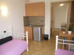 a bedroom with a bed and a kitchen with a sink at Byzance Hotel in Skala