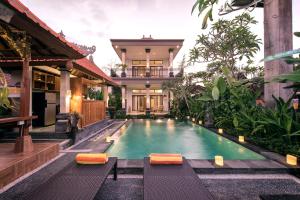 a swimming pool in front of a house at Griya Private Villa in Ubud