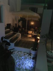 a patio with chairs and an umbrella at night at Byzance Hotel in Skala