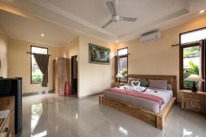 a bedroom with a bed in a room with windows at Griya Private Villa in Ubud