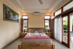 a bedroom with a large bed and windows at Griya Private Villa in Ubud