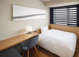 a bedroom with a bed and a desk with a desk at HATAGO INN Fukushima Hirono in Hirono