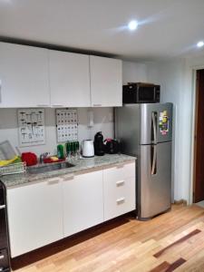 eine Küche mit weißen Schränken und einem Kühlschrank aus Edelstahl in der Unterkunft Avenida Cabildo 1535 in Buenos Aires