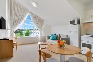 a living room with a kitchen and a table with fruit on it at Aligned Corporate Residences Williamstown in Williamstown