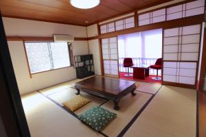 a room with a table and some chairs and windows at Riverside Stay Kanazawa in Kanazawa