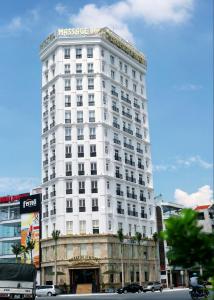 ein hohes weißes Gebäude in einer Stadtstraße mit Autos in der Unterkunft LakeSide 2 Hotel Nam Định in Như Thức