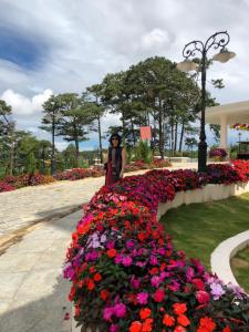 uma mulher a andar por um jardim de flores em My Anh Guest House em Da Lat