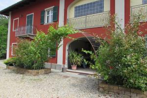 a red house with a balcony and some plants at B&B Cascina Rossa in Asti