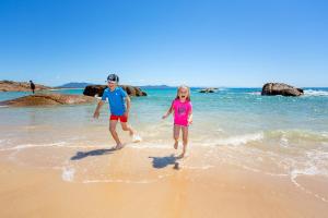 two people walking on a beach near the ocean at NRMA South West Rocks Holiday Park in South West Rocks