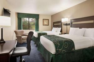 une chambre d'hôtel avec deux lits et une chaise dans l'établissement Travelodge by Wyndham Brunswick near Fredrick, à Brunswick