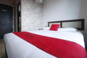 RedDoorz @ Batu Aji Batam في باتام سنتر: سرير أبيض كبير عليه بطانية حمراء