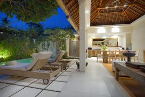 an outdoor patio with a hot tub and a table and chairs at Villa Bali Asri Batubelig in Seminyak