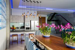 a kitchen and dining room with a wooden table with flowers at Villa Momo, Kata Phuket in Kata Beach