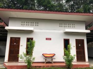 una casa blanca con una silla roja delante en Thanathorn Guesthouse, en Trang
