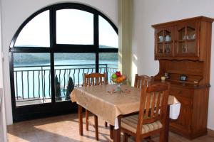 ein Esszimmer mit einem Tisch, Stühlen und einem Fenster in der Unterkunft Apartments Maria in Tisno