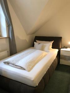 Landhotel Menke في بريلون: سرير بشرشف ووسائد بيضاء في الغرفة