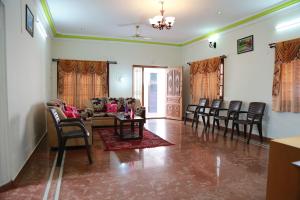 uma sala de estar com cadeiras, um sofá e uma mesa em Coimbatore Home Stay & Serviced Apartment em Coimbatore