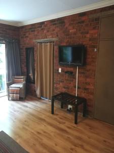 a living room with a brick wall and a flat screen tv at 24 Onvrey Guest House in Boksburg