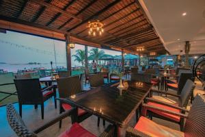 ein Restaurant mit Tischen und Stühlen und Meerblick in der Unterkunft Bintan Spa Villa Beach Resort & Spa in Teluk Bakau