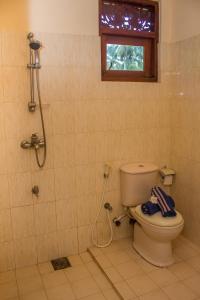a bathroom with a toilet and a shower with a window at Sakura Villa Bentota in Bentota