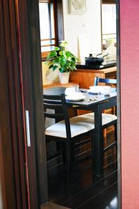 Guesthouse Mio في أوميهاتشيمان: طاولة طعام مع كراسي وطاولة مع نبات