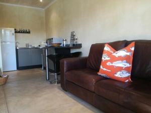 uma sala de estar com um sofá castanho e uma cozinha em River Cottage em Kenton on Sea