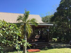 a wooden cabin with a palm tree in a yard at YOISAMA Sunrise Beach House in Ishigaki Island