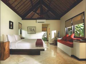 a bedroom with a large bed and a red couch at Qunci Villas Resort in Senggigi