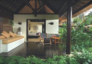 a room with a bed and a table on a deck at Qunci Villas Resort in Senggigi