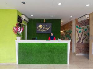 a woman standing behind a green counter in a lobby at I Leaf Boutique Hotel in Johor Bahru