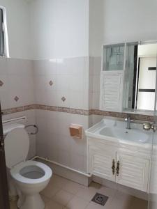 a white bathroom with a toilet and a sink at Api Api Centre Apartment Homestay in Kota Kinabalu