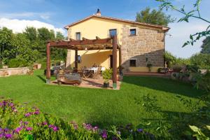 un jardín con una casa y una pérgola en FicOlivo en Pitigliano