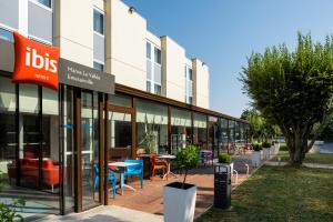 un bâtiment avec des tables et des chaises à l'extérieur dans l'établissement ibis Paris Marne la Vallee Emerainville, à Émerainville