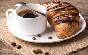 a pastry on a plate next to a cup of coffee at Sofia Hotel in Perm