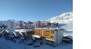 um edifício na neve ao lado de uma montanha em Appartement traversant résidence chaput 2 - 2 pièces - 6 personnes - vue sur front de neige em La Toussuire