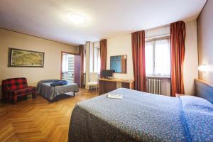 a hotel room with a bedroom with two beds and a chair at Hotel Roma in Aosta